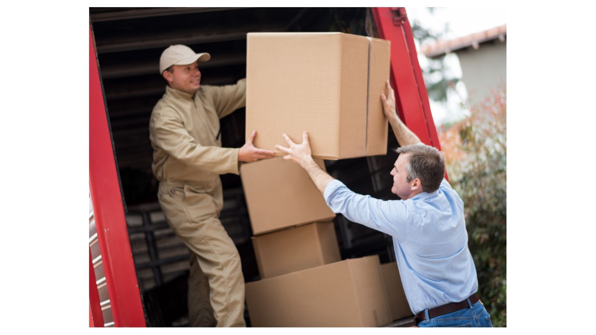 Movers loading stacked cardboard boxes into a red moving truck