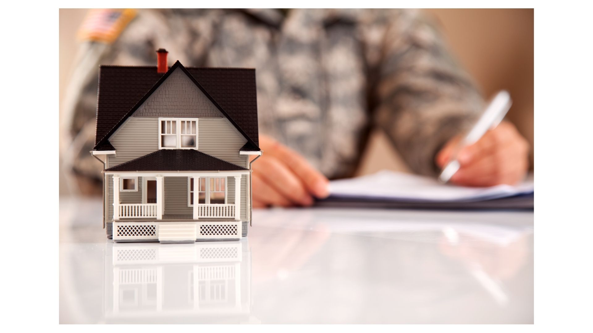 Service member in uniform signing paperwork next to a model home, planning a PCS move