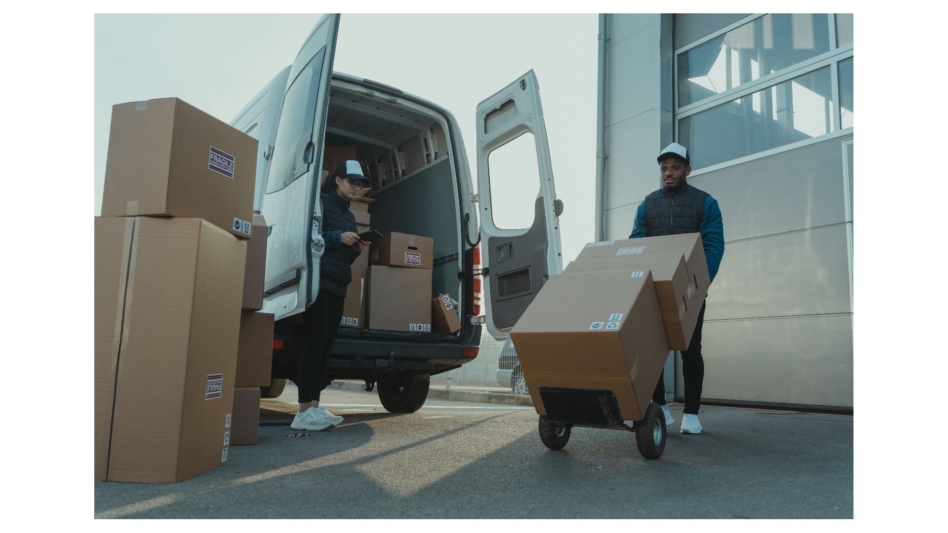 Two Half Price Movers crew members loading labeled fragile boxes into a moving van on a sunny San Antonio day
