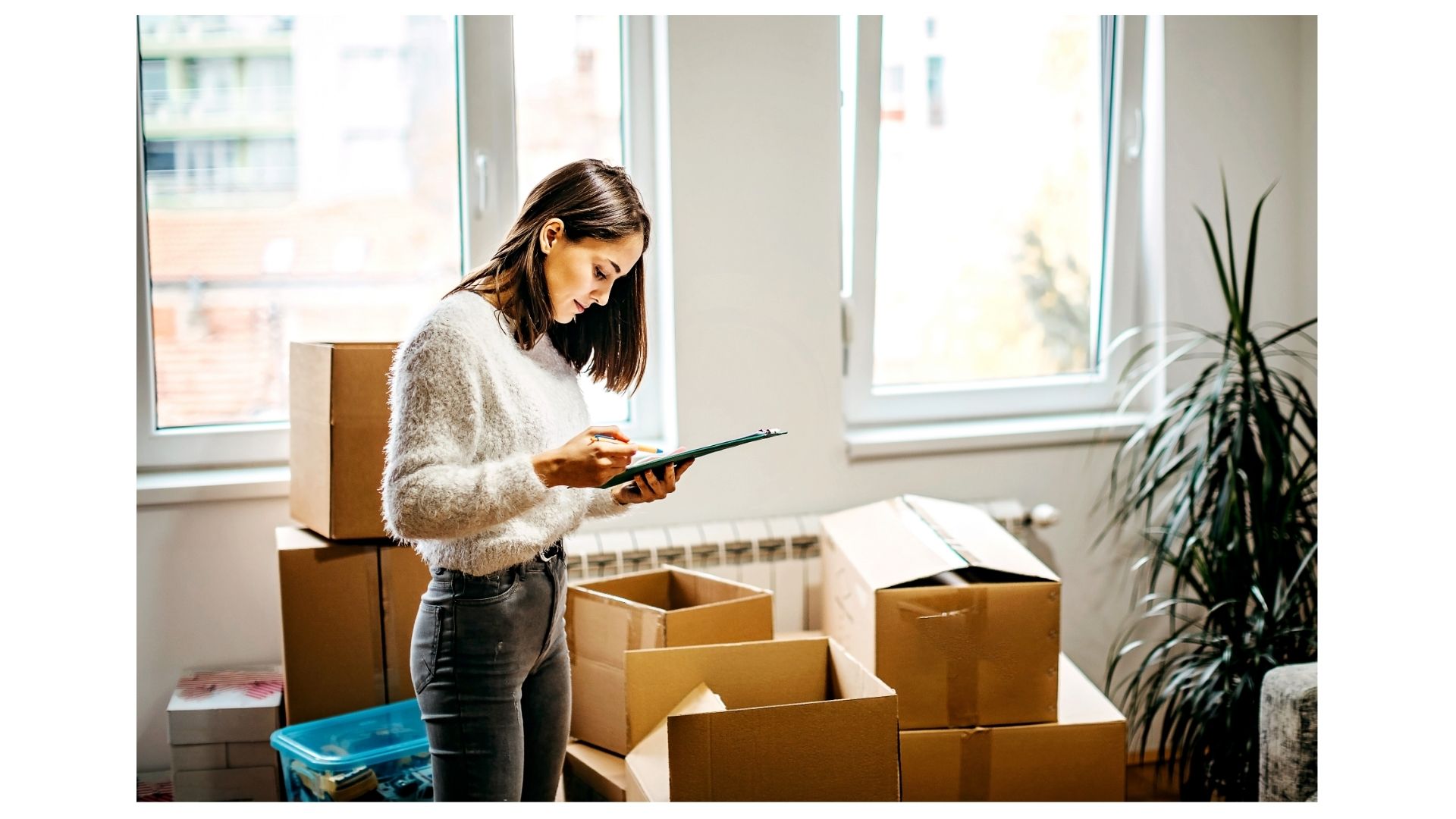Long distance moving cost Texas — woman with clipboard taking inventory of moving boxes during a residential relocation