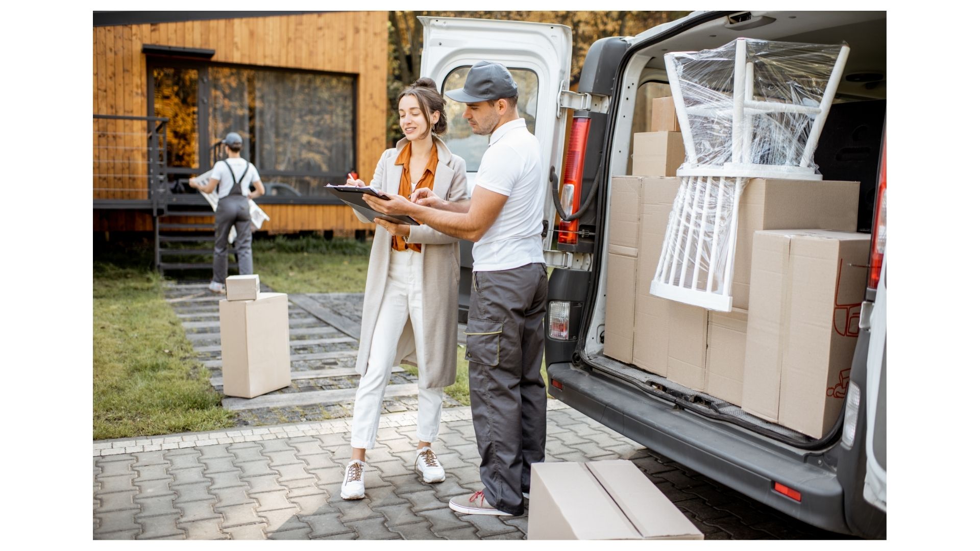 Two professional movers with a clipboard and a loaded moving van outside a customer's home in San Antonio
